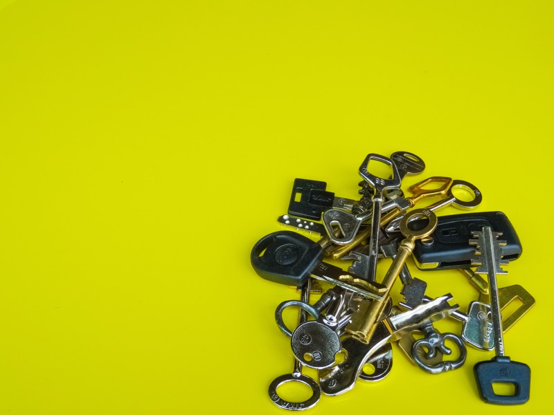 Un trousseau de clés anciennes, de sécurité et de voiture à télécommande, sur fond jaune